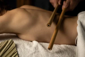 Terapeuta masażu wykonuje intensywny masaż bambusowymi kijkami na plecach klienta, rozluźniając głębokie napięcia mięśniowe