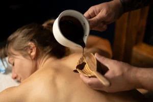 Terapeuta masażu aplikuje gorącą czekoladę na plecach klienta podczas luksusowego zabiegu spa w orientalnym gabinecie