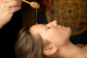 Terapeuta masażu aplikuje naturalny miód na twarz klienta podczas terapeutycznego masażu miodem w orientalnym wnętrzu